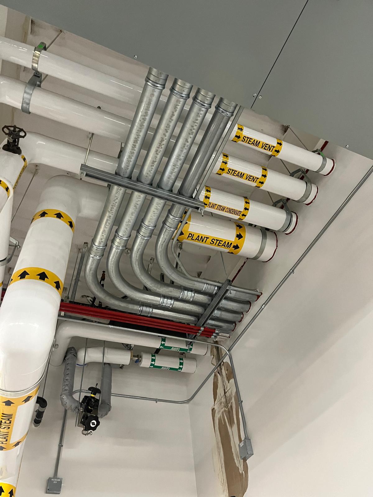 Labelled insulated piping in a clean, finished ceiling space